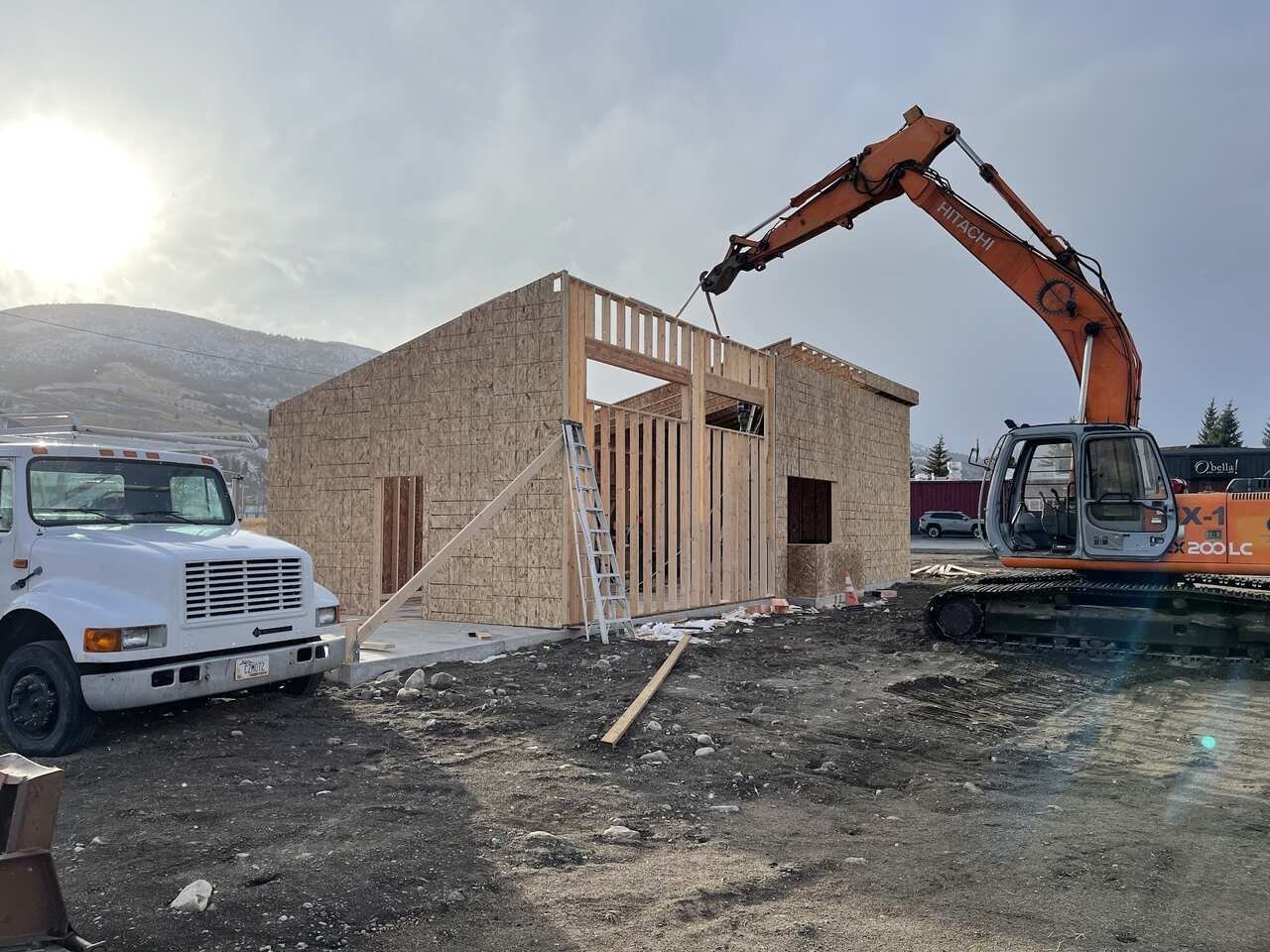 Excavator working beside a newly framed commercial building