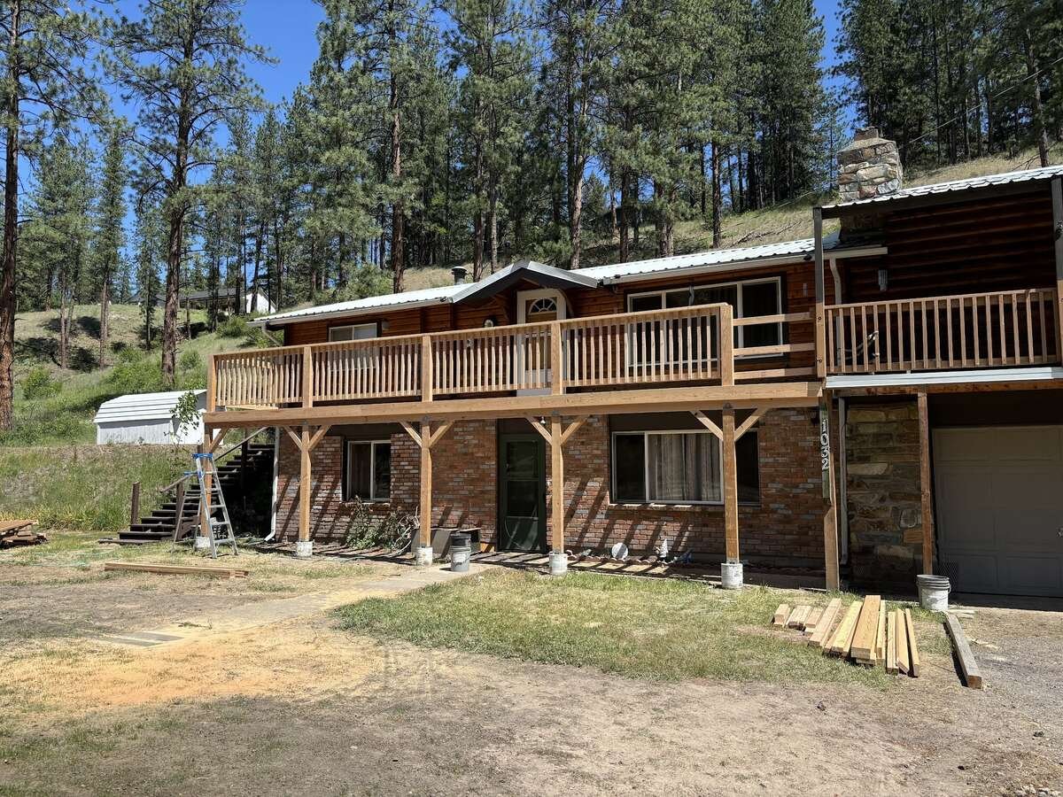 Log and brick home with a newly built wraparound deck and stairs