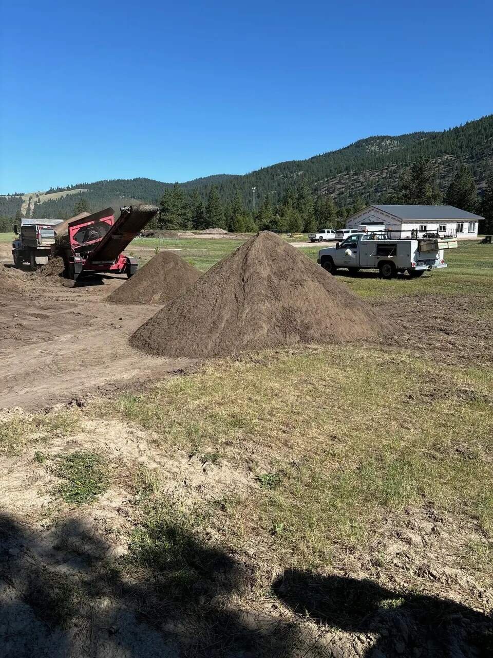 Topsoil piles and a screening plant on a rural western Montana job site